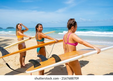 Group Of Asian Woman Surfer In Swimwear Holding Surfboard Walking Together On Tropical Beach In Sunny Day. Happy Female Friends Enjoy Outdoor Activity Lifestyle Water Sport Surfing On Summer Vacation