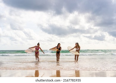 Group Of Asian Woman Surfer In Swimwear Holding Surfboard Walking Together On Tropical Beach At Summer Sunset. Female Friends Enjoy Outdoor Activity Lifestyle Water Sport Surfing On Travel Vacation