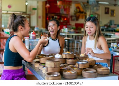 Group of Asian woman tourist eating Chinese food steamed dumpling in bamboo steamer with chopsticks in Chinese restaurant. Happy female friends enjoy eating and travel together on summer vacation.
