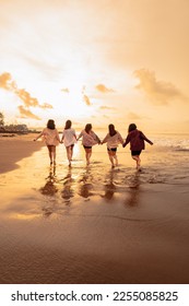 a group of Asian women is running with their friends happily on the beach in the afternoon - Shutterstock ID 2255085825