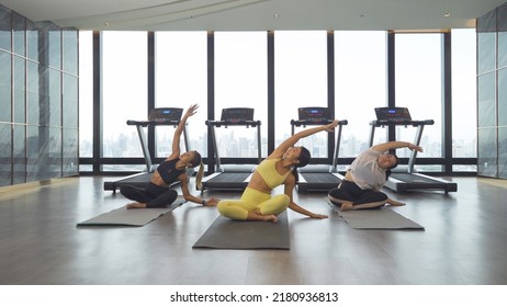 Group of Asian women in yoga class club doing exercise and yoga at fitness center or gym. Indoor in sport and recreation concept. People lifestyle activity with urban city view. - Powered by Shutterstock