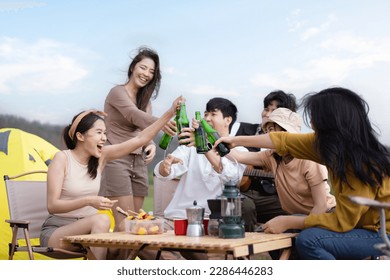 Group of Asian young adult people enjoy drinking a beer together during camping at the park. Asian young women and men celebrating with a bottle of a beer together. - Powered by Shutterstock