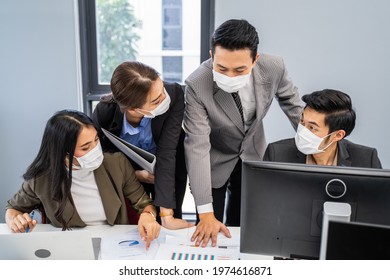 Group Of Asian Young Business People Working On Computer In Office With New Normal Lifestyle. Man And Woman Wear Protective Face Mask Due Covid, Brainstorm And Share Idea In Team Working As Teamwork.