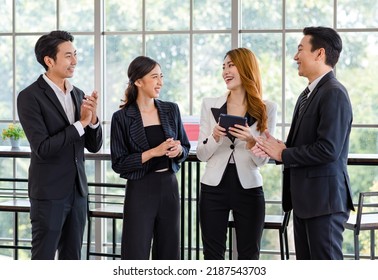 Group of Asian young happy cheerful millennial professional successful male businessman and female businesswoman in formal suit standing smiling talking together taking coffee break resting relaxing. - Powered by Shutterstock
