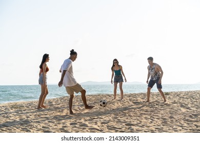 Group of Asian young man and woman play soccer on the beach together. Attractive friend traveler feel happy and relax, having a football game while travel for holiday vacation in tropical sea island. - Powered by Shutterstock