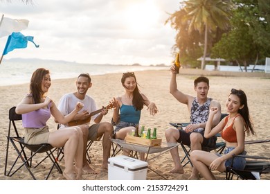 Group of Asian young man and woman having party on the beach together. Attractive happy friends traveler singing and dancing while camping at seaside enjoy holiday vacation trip in tropical sea island