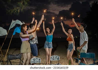 Group of Asian young man and woman having party on the beach at night. Attractive friends traveler sing and dancing while camping at seaside enjoy holiday vacation trip in tropical sea island together - Powered by Shutterstock