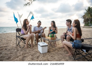 Group of Asian young man and woman having party on the beach together. Attractive happy friends traveler singing and dancing while camping at seaside enjoy holiday vacation trip in tropical sea island - Powered by Shutterstock