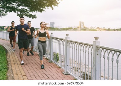 Group Of Asian Young People Running Along The River