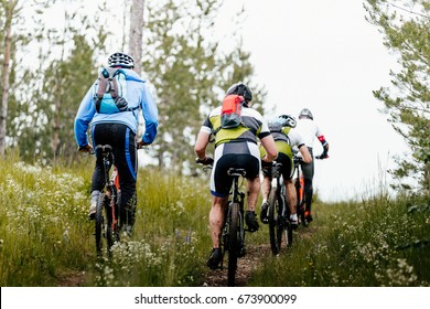 Group Of Athletes Mountain Biking On Forest Trail