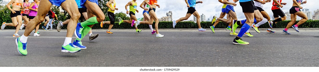 group athletes runners: men and women running city marathon in background of buildings