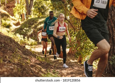 Group Of Athletes Runners Run Uphill Trail. Men And Women Running A Marathon Race.