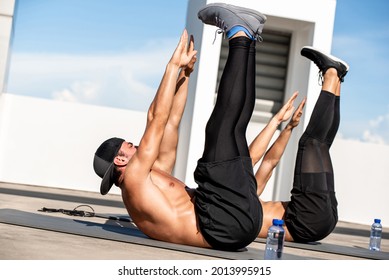Group of athletic men doing toe touch crunch workout exercise outdoors on building rooftop floor - Shutterstock ID 2013995915