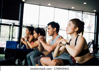 Group Of Athletic Young Asian People In Sportswear Doing Squat And Exercising At The Gym. Intense Workout And Healthy Lifestyle Concept