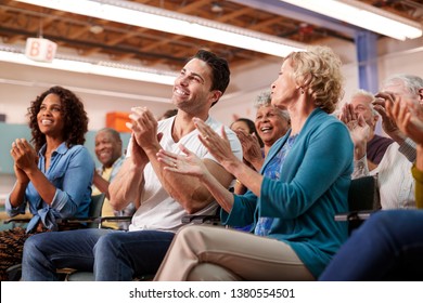 Group Attending Neighborhood Meeting In Community Center Clapping