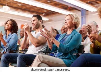 Group Attending Neighborhood Meeting In Community Center Clapping