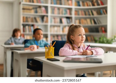 Group of attentive and diverse school children sitting at their desks in classroom, focusing intently on their teacher, absorbing knowledge and demonstrating respectful listening during the lesson - Powered by Shutterstock