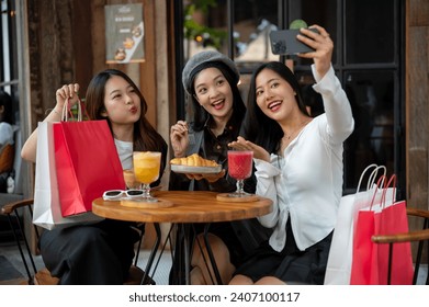 Group of attractive Asian female friends are taking selfies with a smartphone while hanging out at a restaurant or cafe together. City life, travel, lifestyle - Powered by Shutterstock