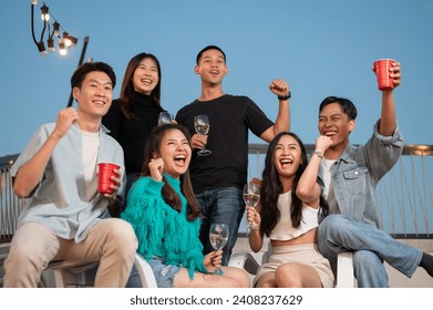 Group of attractive, cheerful Asian friends are enjoying partying on a rooftop bar and restaurant, having fun and celebrating special moments together. city life, friendship, night out - Powered by Shutterstock