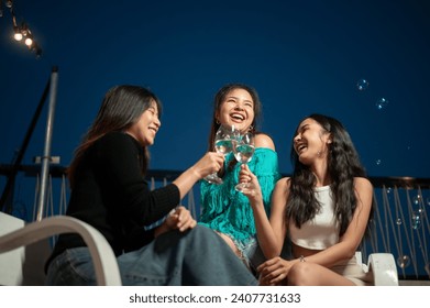 Group of attractive and cheerful Asian girls are enjoying partying on a rooftop bar together and having a fun night out, enjoying talking and drinking champagne. Friendship and celebration concepts - Powered by Shutterstock