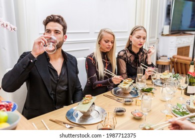 Group Of Attractive Friends Eating Sushi And Drinking Wine At A Private Dinner Party