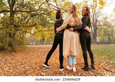 Group Of Attractive Girls Hugging In Beautiful Autumn Season Park, Back Turned Towards Camera 