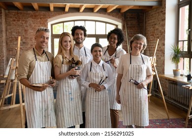 Group attractive optimistic multiethnic talented students   aged friendly teacher photoshoot in artistic workshop  hold paintbrushes pose smile look at camera  Art  school education  hobby concept