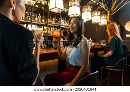 Group of Attractive woman enjoy and fun hangout nightlife meeting and drinking fancy cocktail together at luxury bar. Happy female friends celebrating holiday event party at nightclub in the city
