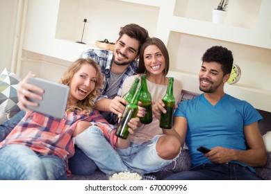 Group of attractive young people sitting on the sofa, doing selfie and smiling.