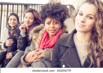 Group Of Attractive Young Women Of Different Ethnics Sitting On Stairs And Smiling At Camera - Four Students Sitting Outside University - Best Friends Spending Time Together