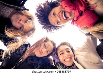 Group Of Attractive Young Women Of Different Ethnics Hugging In A Circle - Four Students Smiling At Camera - Best Friends Spending Time Together