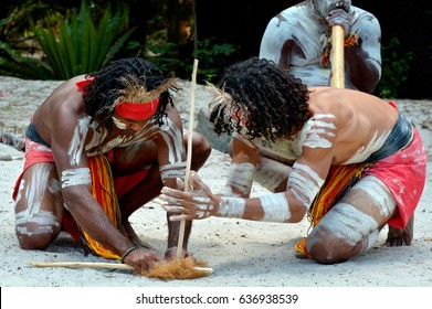 Group Of Australian Aboriginals Men Demonstrating Fire Making Craft During Aboriginal Culture Show In The Far Tropical North Of Queensland, Australia.