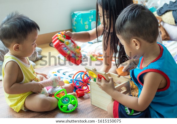 Group of baby friend playing toy\
together in living home sister and brother\
relationship
