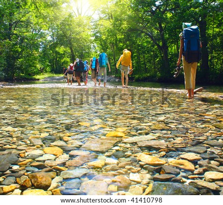 Group of backpackers fording cold river