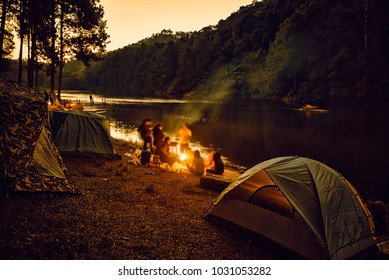 Group of backpackers relaxing near campfire, tourist background.