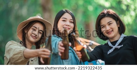 Group beautiful Asian women friends travelers  relaxing at front of camping tent, They enjoy to talking and drinking beer with fun and happy together