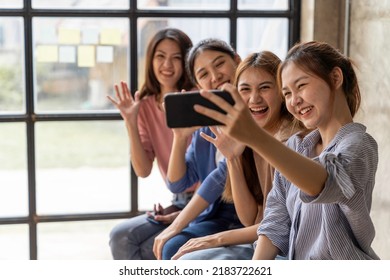 Group Of Beautiful Asian Women Holding Cell Phones To Take Pictures With A Group Of Friends At Work. Video Call By Using FaceTime, Face ID Recognition Technology, Taking A Picture