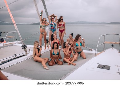 Group Of Beautiful And Attractive Girls In Colorful Bikini And Sunglasses On A White Luxury Boat Having A Good Time Drinking Champagne. Outdoor Posing. The Concept Of A Bachelorette Party.