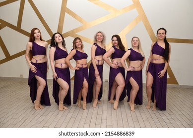 A group of beautiful girls in the outfits of oriental dancers in the studio stand in a row posing as in an oriental harem