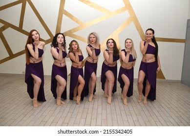 A group of beautiful girls in the outfits of oriental dancers in the studio stand in a row posing as they blow a kiss in an oriental harem