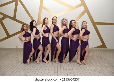 A group of beautiful girls in the outfits of oriental dancers in the studio stand in a row posing as in an oriental harem