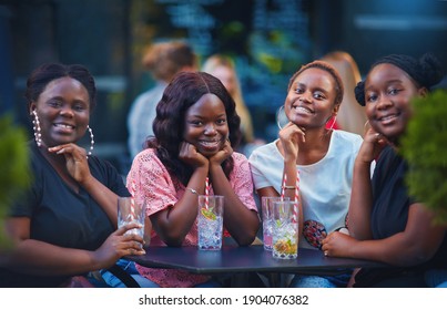 a group of beautiful happy african american women, girls chilling out at summer outdoor cafe, drinking cocktails and having fun