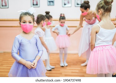 Group of beautiful little girls with protective face masks practicing ballet at dancing class. Coronavirus, Covid-19 concept.