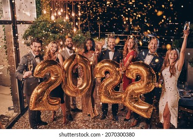 Group of beautiful people in formalwear carrying gold colored numbers and smiling - Shutterstock ID 2070300380