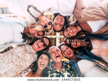 Group of beautiful people in friendship enjoying the party outside on the terrace. Large smiles for the photo from below. Nine women together
