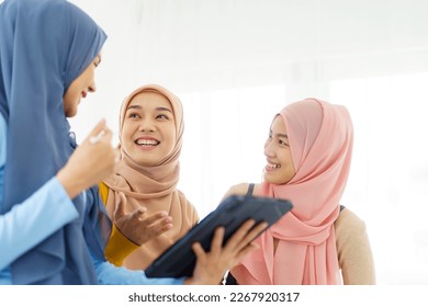 Group of a beautiful smart Asian muslim woman standing in the room and having a discussion together. Modern muslim society concept, women muslim student talking. - Powered by Shutterstock