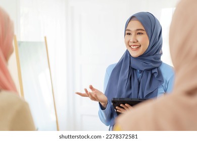 Group of a beautiful smart Asian muslim woman standing in the room and having a discussion together. Modern muslim society concept, women muslim student talking. - Powered by Shutterstock