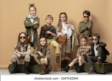 The Group Of Beautiful Teen Girls And Boys On A Pastel Studio Background. Stylish Young Teen Girls Posing At Studio. Safari Style. Classic Style. Teen And Kids Fashion Concept. Children's Fasion