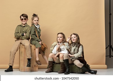 The group of beautiful teen girls and boys on a pastel studio background. Stylish young teen girls posing at studio. Safari style. Classic style. Teen and kids fashion concept. children's fasion