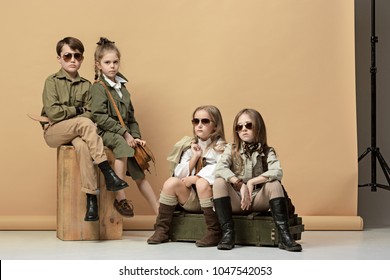 The Group Of Beautiful Teen Girls And Boys On A Pastel Studio Background. Stylish Young Teen Girls Posing At Studio. Safari Style. Classic Style. Teen And Kids Fashion Concept. Children's Fasion